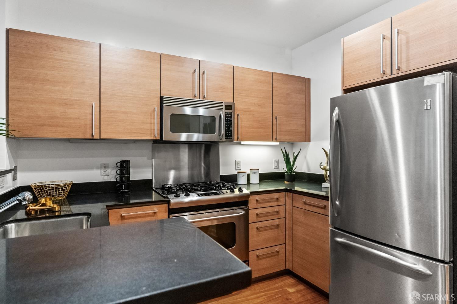 200 2nd Street, Unit 103 Oakland, CA 94607 - Photo 12 of 31 a kitchen with stainless steel appliances granite countertop a refrigerator a stove a sink cabinets and a wooden floor