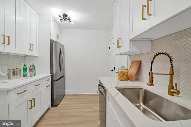 a kitchen with a refrigerator sink and white cabinets with wooden floor