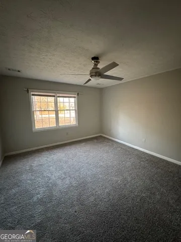 an empty room with windows and fan