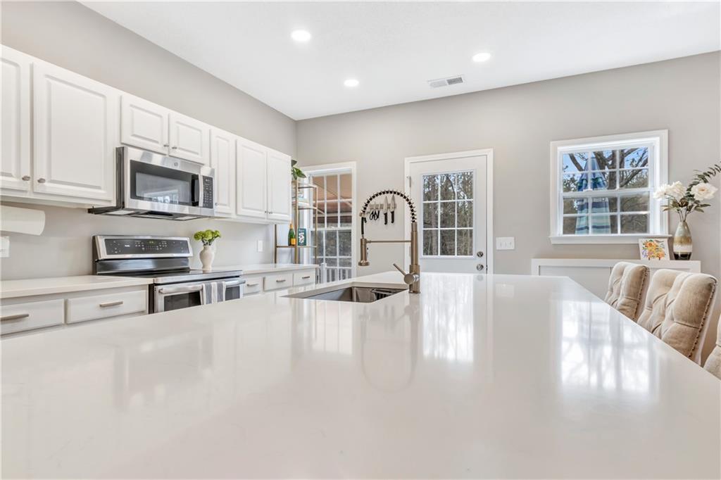 68 Skyview Road Senoia, GA 30276 - Photo 12 of 51 a kitchen with stainless steel appliances granite countertop a stove top oven a sink a dining table and chairs with white cabinets