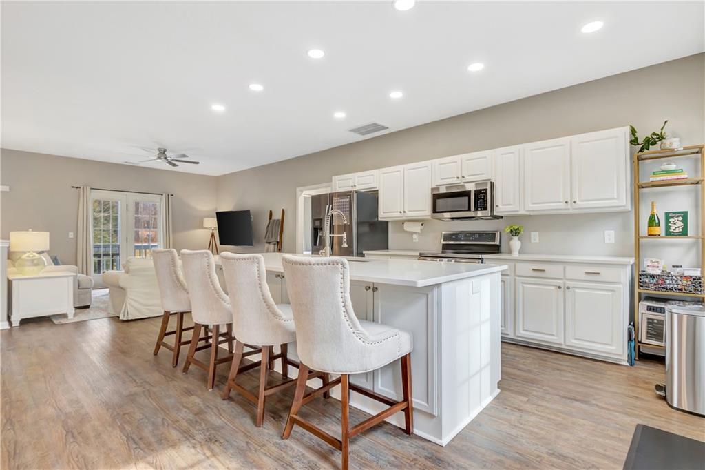 68 Skyview Road Senoia, GA 30276 - Photo 10 of 51 a kitchen with stainless steel appliances kitchen island granite countertop a refrigerator a stove a sink a dining table and chairs with wooden floor
