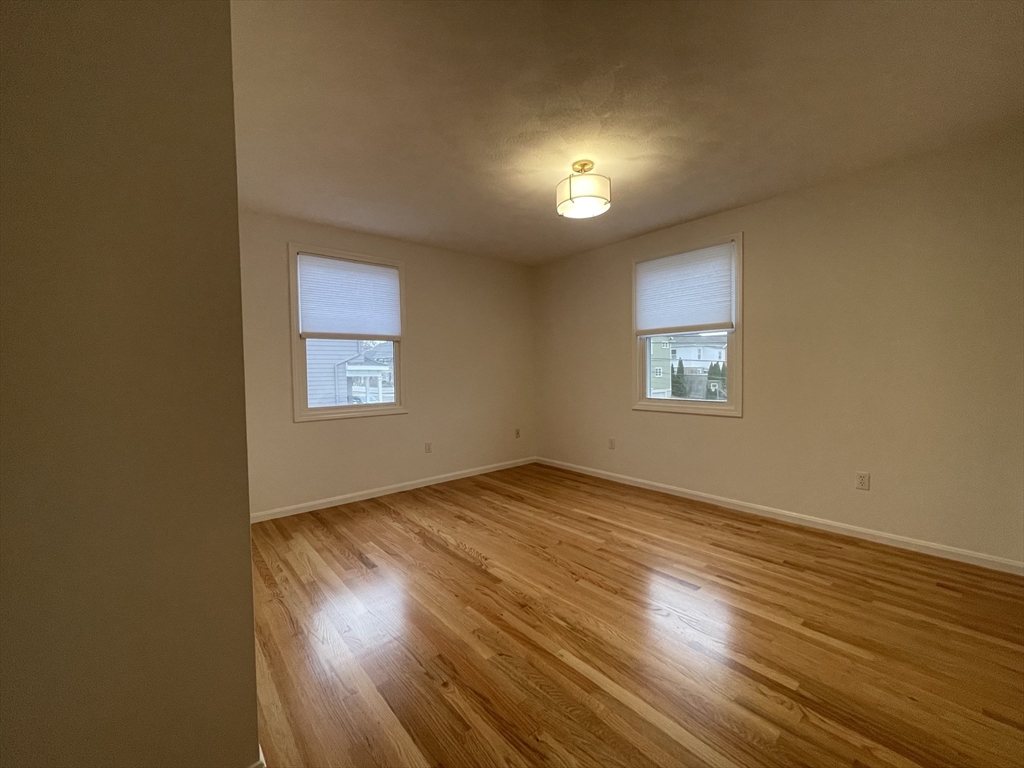 196 Linwood Avenue, Unit 196 Newton, MA 02460 - Photo 24 of 37 an empty room with wooden floor and windows