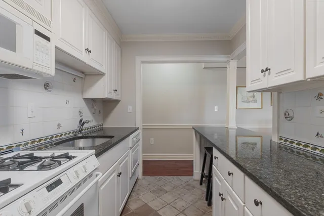 a kitchen with granite countertop a sink stove and cabinets