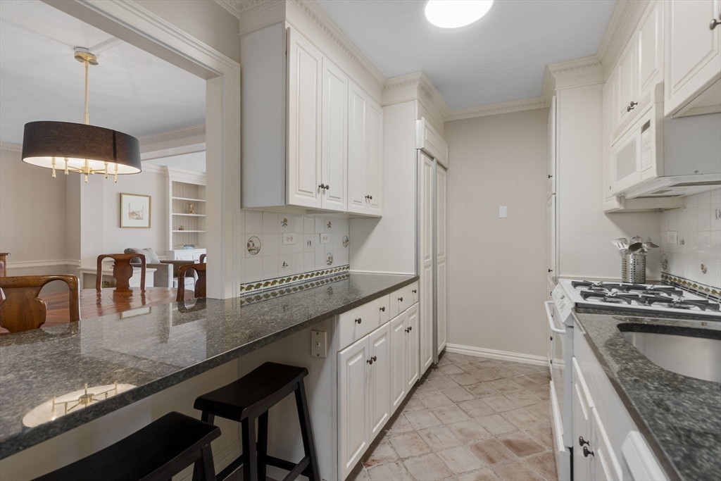 6 Whittier Place, Unit 14N&O Boston, MA 02114 - Photo 5 of 31 a kitchen with granite countertop a sink a stove and a wooden cabinets