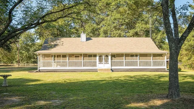 a view of a house with a big yard and large trees