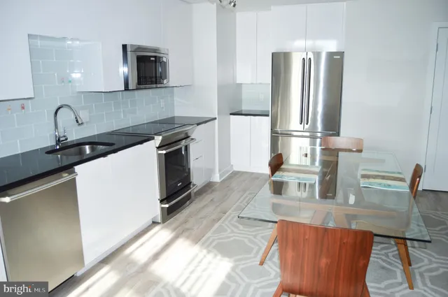 a kitchen with stainless steel appliances granite countertop a sink and a refrigerator