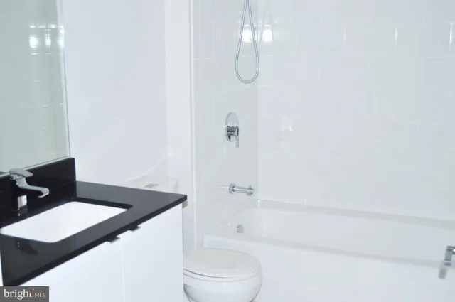 a bathroom with a granite countertop sink a toilet and shower