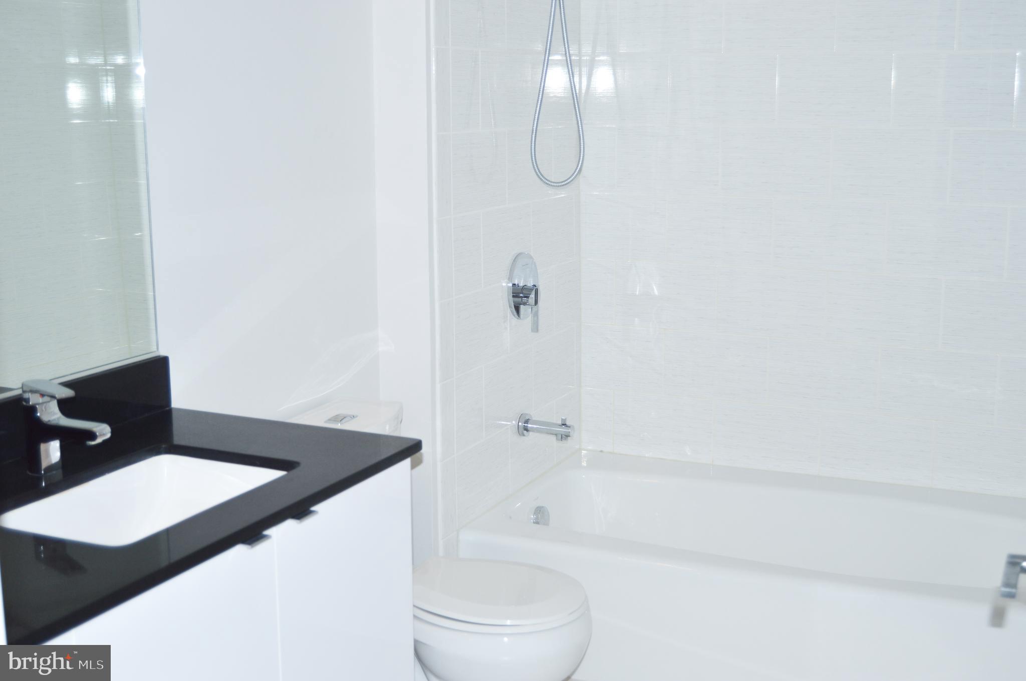 460 New York Avenue Northwest, Unit 805 Washington, DC 20001 - Photo 10 of 21 a bathroom with a granite countertop sink a toilet and shower