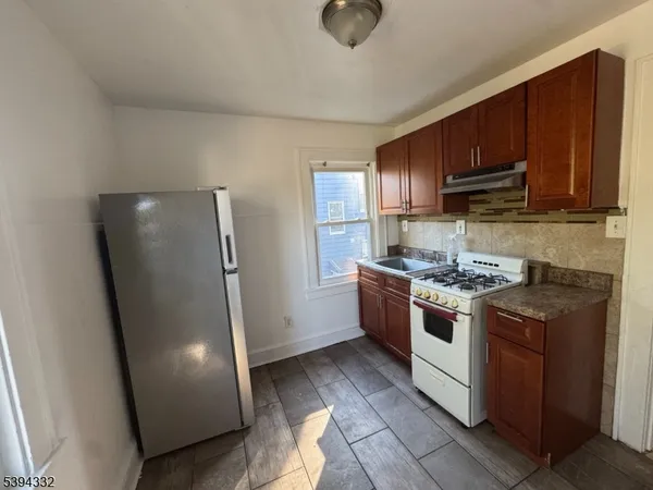 a kitchen with stainless steel appliances granite countertop a refrigerator a stove and a sink