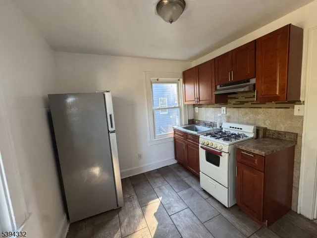 a kitchen with stainless steel appliances granite countertop a refrigerator a stove and a sink