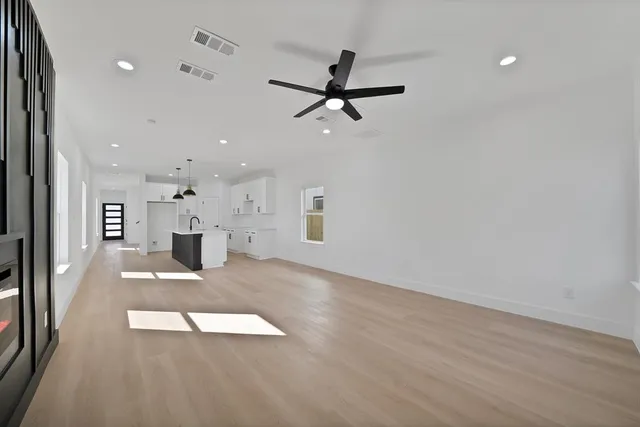 an empty room with wooden floor and windows