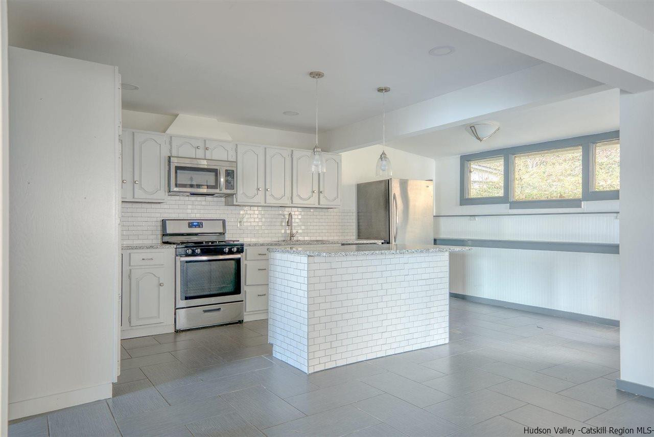 94 River Road Ulster Park, NY 12487 - Photo 16 of 31 a kitchen with kitchen island a stove a sink and white cabinets