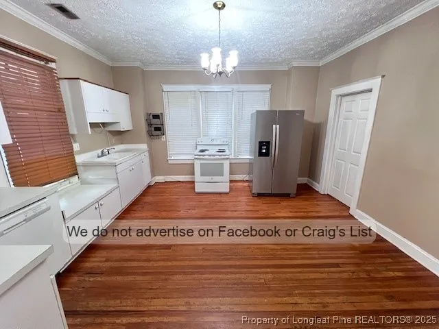 a living room with stainless steel appliances furniture a rug and a chandelier