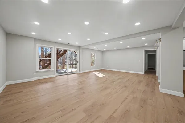a view of an empty room with wooden floor and window