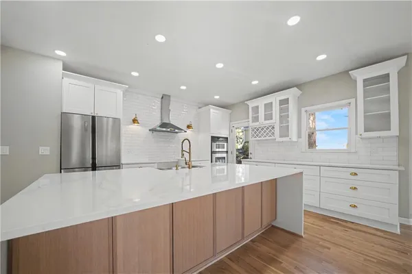 a large kitchen with stainless steel appliances a large counter top a sink and a refrigerator