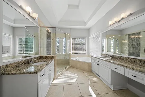 a large white kitchen with granite countertop a sink and cabinets