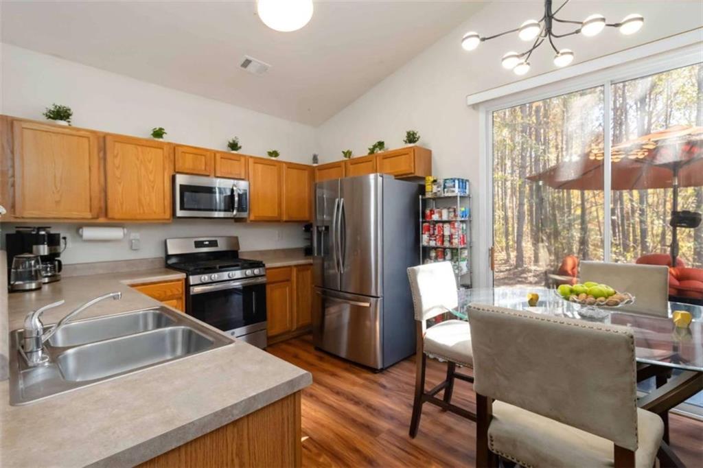 782 Jasperson Court Fairburn, GA 30213 - Photo 10 of 30 a kitchen with stainless steel appliances granite countertop a refrigerator a stove top oven a sink dishwasher a dining table and chairs with wooden floor