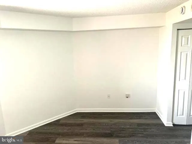 an empty room with wooden floor & closet area