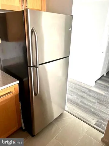 a view of a refrigerator in kitchen and an empty room