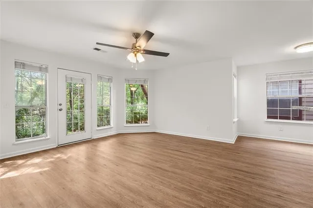 a view of an empty room with wooden floor and a window