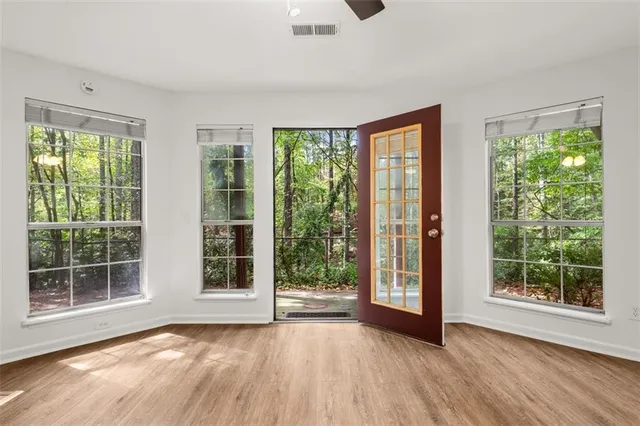 a view of an empty room with wooden floor and a window