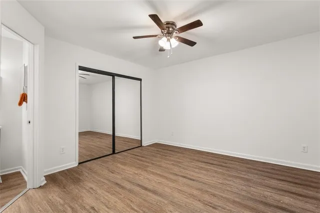 an empty room with wooden floor and fan