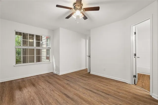 a view of empty room with wooden floor and fan