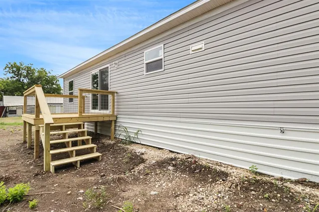 a view of a blue house with a large window and stairs next to a road