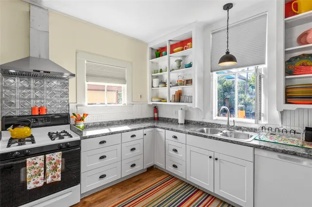 a kitchen with stainless steel appliances a stove a sink and a wooden floor