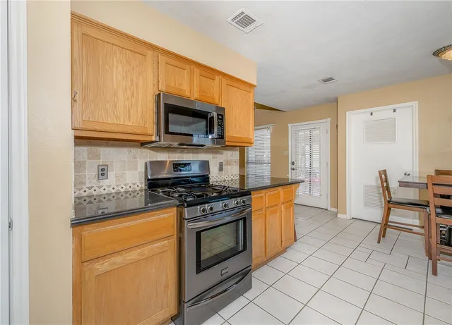 a kitchen with stainless steel appliances granite countertop a stove a sink and a microwave