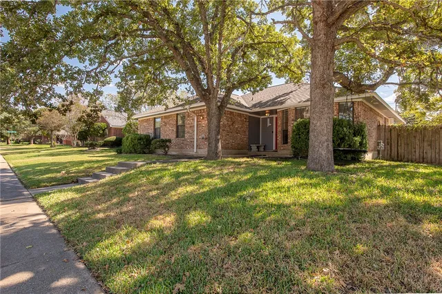 a backyard of a house with large trees and outdoor seating