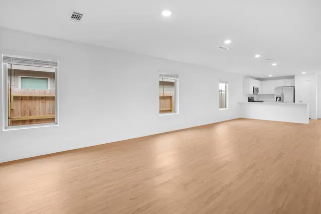a view of an empty room with window and wooden floor