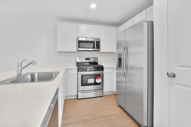 a kitchen with stainless steel appliances a refrigerator sink and white cabinets