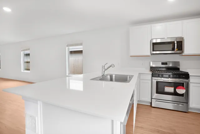 a kitchen with stainless steel appliances granite countertop a stove a microwave and a refrigerator