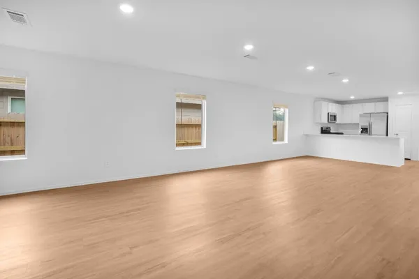a view of empty room with wooden floor and windows