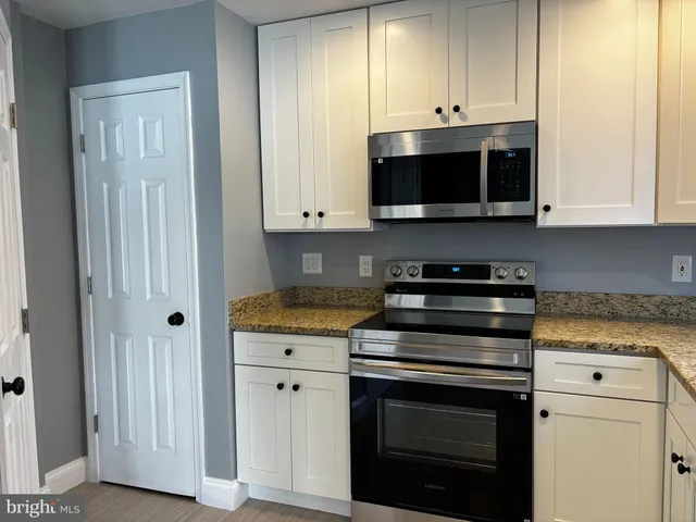 a kitchen with stainless steel appliances granite countertop white cabinets and a stove