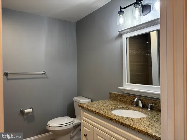 a bathroom with a granite countertop sink a mirror and toilet