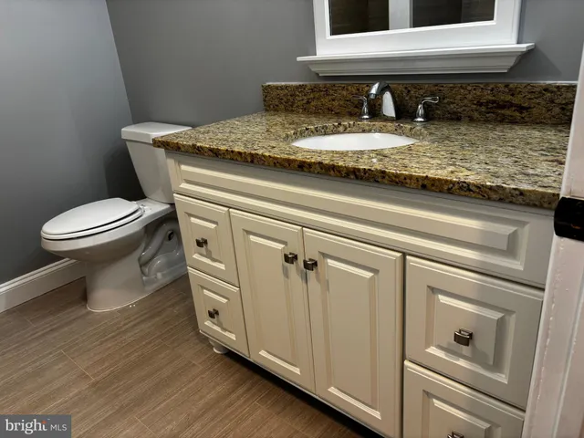 a bathroom with a granite countertop toilet sink and mirror