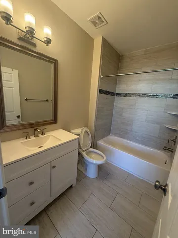 a bathroom with a granite countertop bathtub shower and toilet