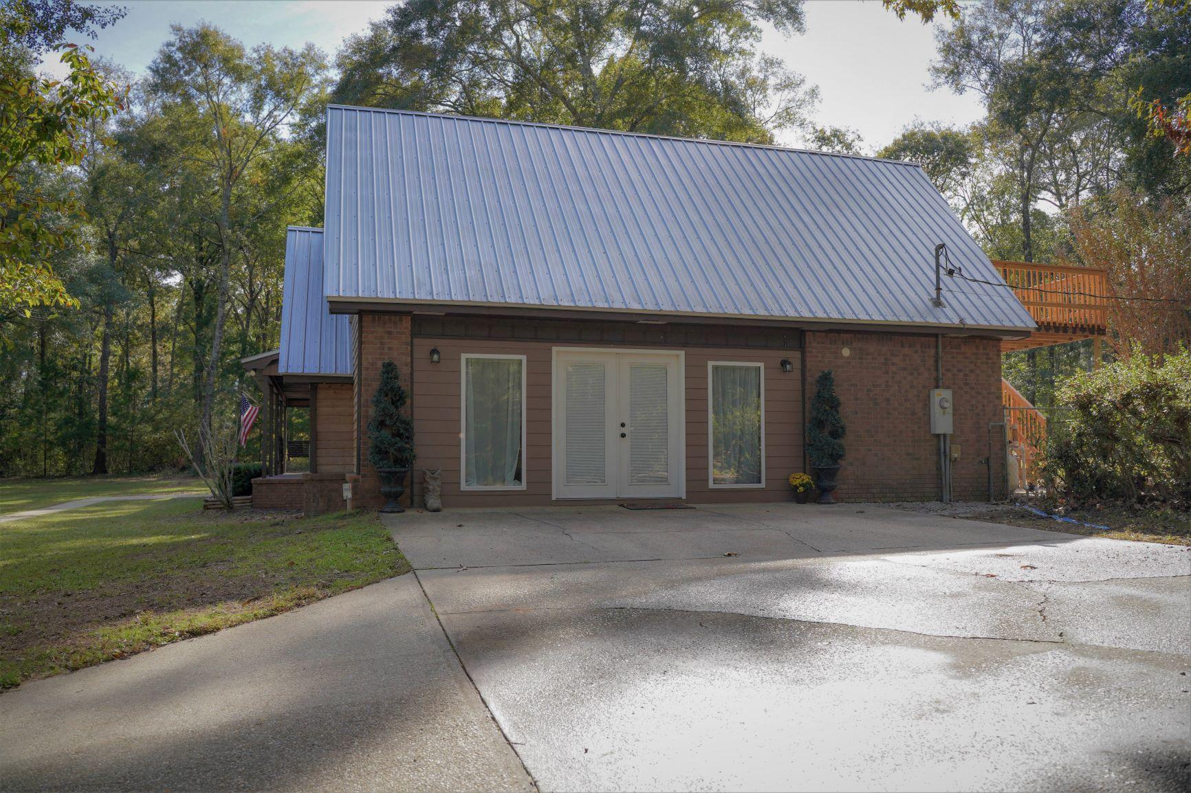 5846 Dairy Road Baker, FL 32531 - Photo 56 of 68 a front view of a house with a garden and trees