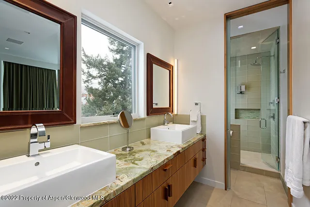 a bathroom with a double vanity sink a mirror and a shower