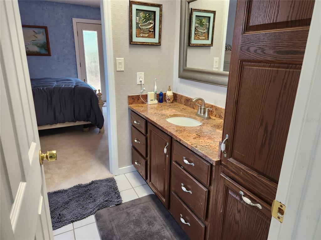 1137 Ponderosa Road Venice, FL 34293 - Photo 26 of 48 a bathroom with a granite countertop sink a mirror and a shower