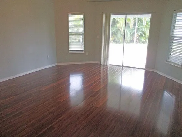 a view of an empty room with wooden floor and a window