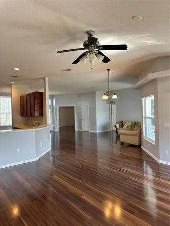 a view of empty room with wooden floor and fan