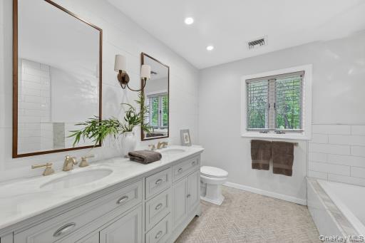 9 Hickory Ridge Road Brewster, NY 10509 - Photo 31 of 50 a bathroom with a double vanity sink a toilet a mirror and window
