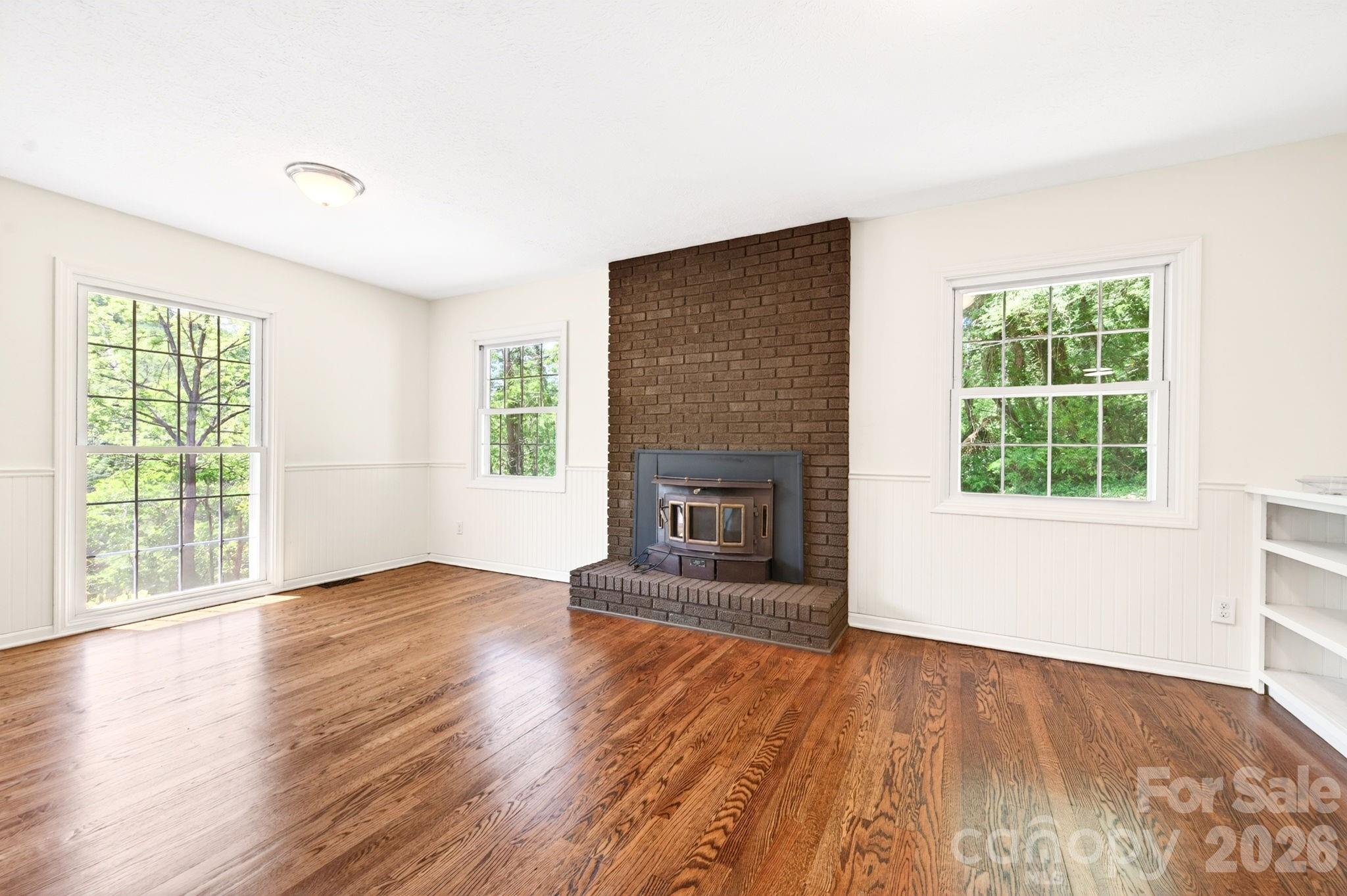 34 Wolfe Cove Road Asheville, NC 28804 - Photo 9 of 42 an empty room with wooden floor fireplace and windows