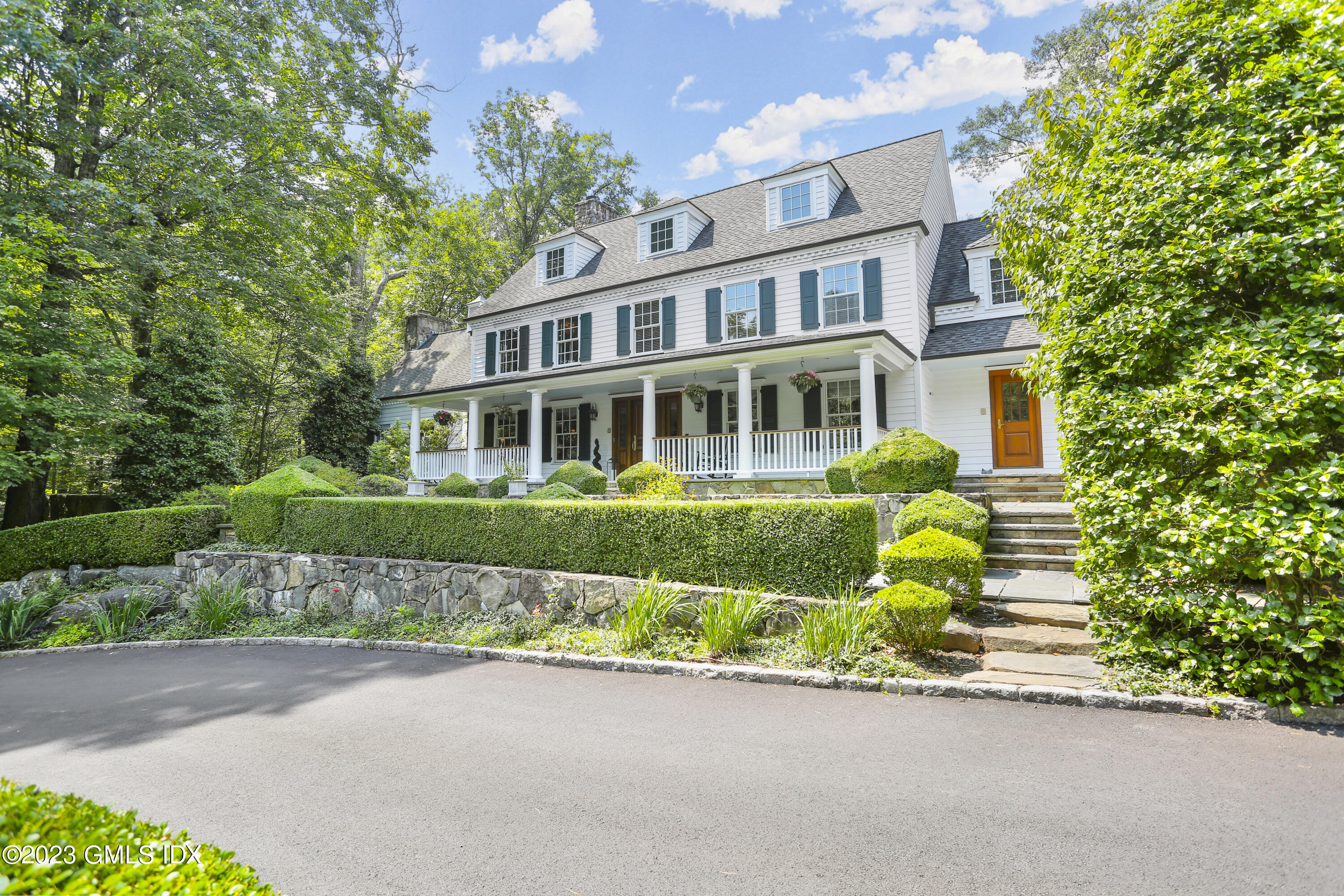 a front view of a house with a garden and a tree