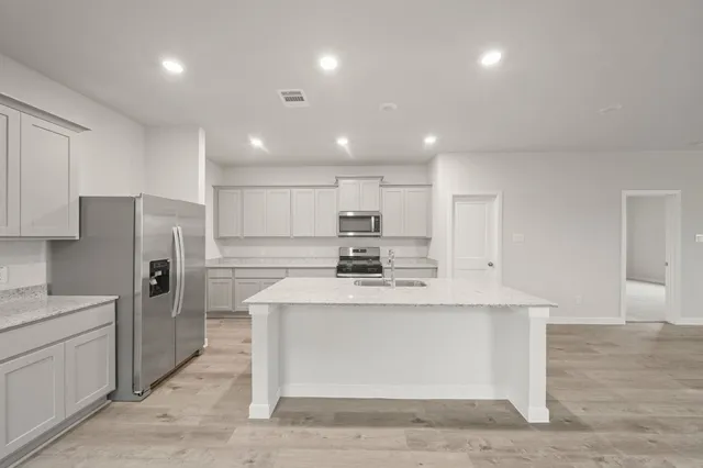 a large white kitchen with a refrigerator a stove and a sink