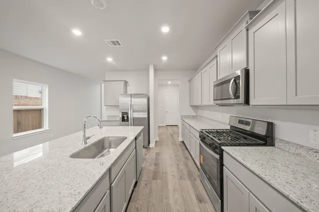 a kitchen with stainless steel appliances granite countertop sink stove and refrigerator