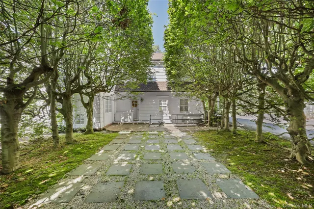 a front view of a house with a garden and trees